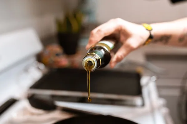 Oil being poured from a bottle in a kitchen
